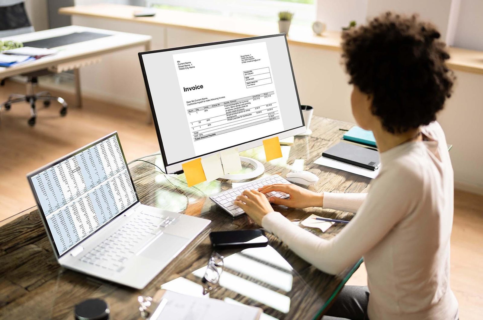 Accountant reviewing an invoice and ledger on screen while preparing an activity statement